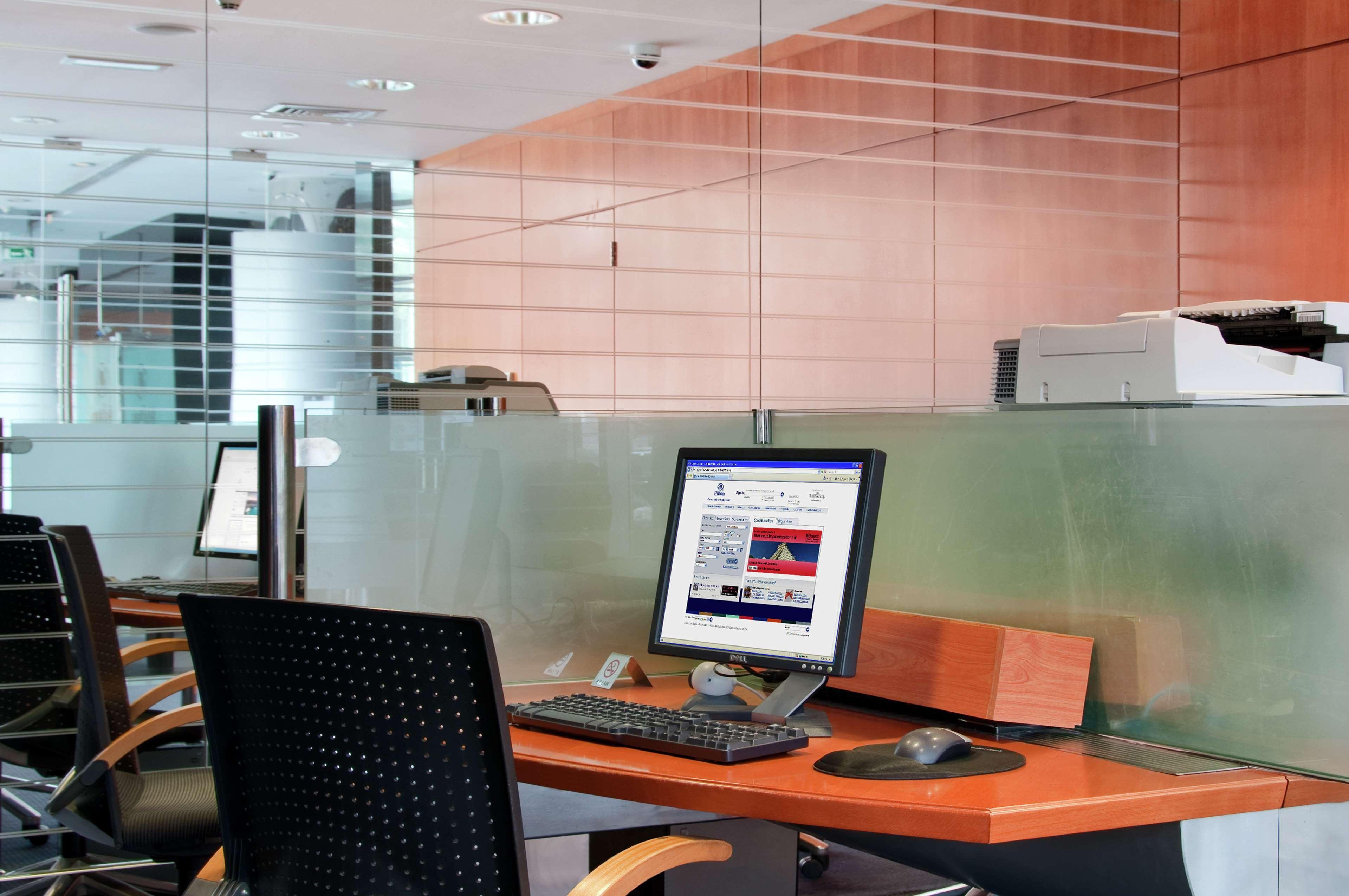 Golden Sands Boutique Hotel-Dubai Creek Съоръжения снимка The photo showcases a modern office space featuring a few workstations. Each workstation includes a computer monitor, keyboard, and mouse, set on a sleek wooden desk. The decor has a minimalist style with glass partitions and wooden paneling, contrib
