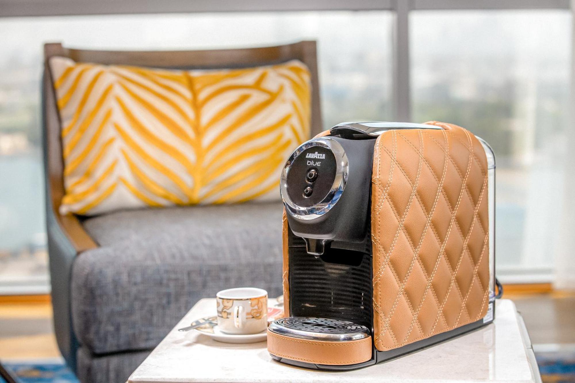 Golden Sands Boutique Hotel-Dubai Creek Екстериор снимка The photo shows a stylish coffee machine with a chic design, featuring a quilted texture in a tan or beige color on one side. It's placed on a light-colored table next to a small coffee cup, which suggests it’s ready for use. In the background, there