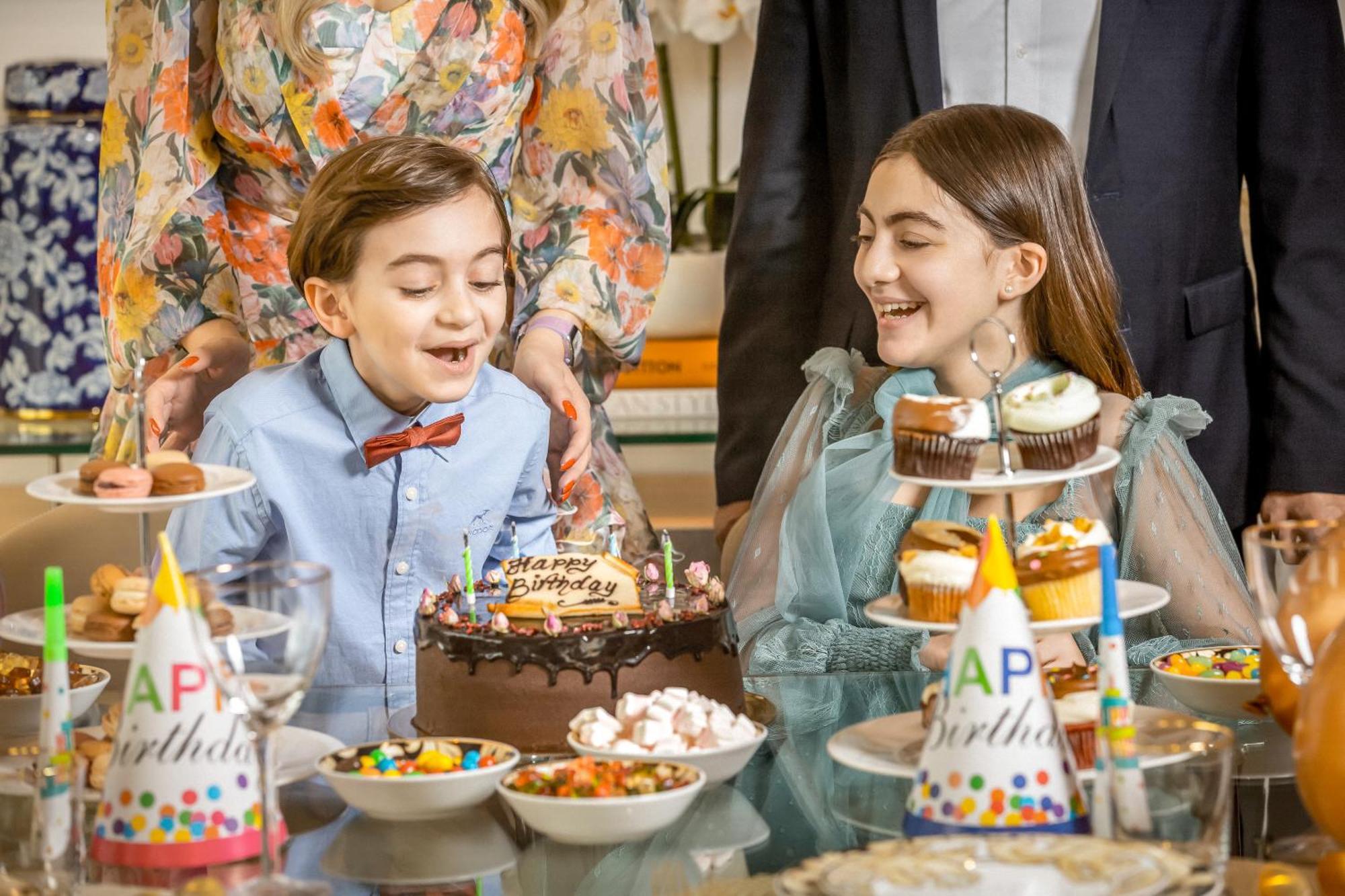 Golden Sands Boutique Hotel-Dubai Creek Екстериор снимка The photo shows a festive birthday celebration. Two children, a boy and a girl, are smiling and enjoying the moment. The boy, wearing a light blue shirt with a bow tie, sits in front of a chocolate birthday cake that says "Happy Birthday." The girl, 
