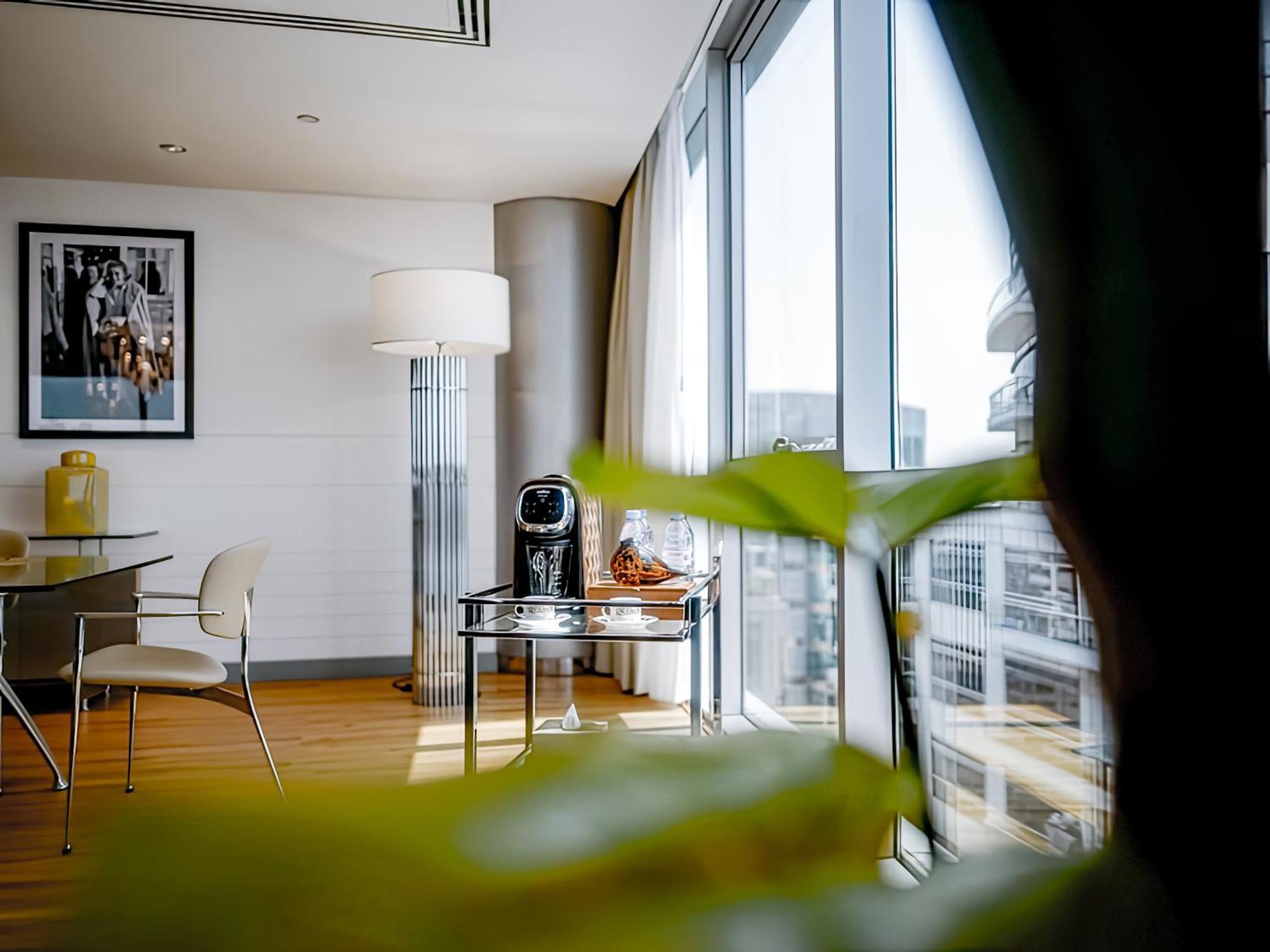 Golden Sands Boutique Hotel-Dubai Creek Екстериор снимка The photo depicts a modern, stylish interior of a room, likely a hotel or a contemporary living space. There are large windows that allow natural light to flood in, showcasing a view of the outside environment. 

In the foreground, there's a green pl