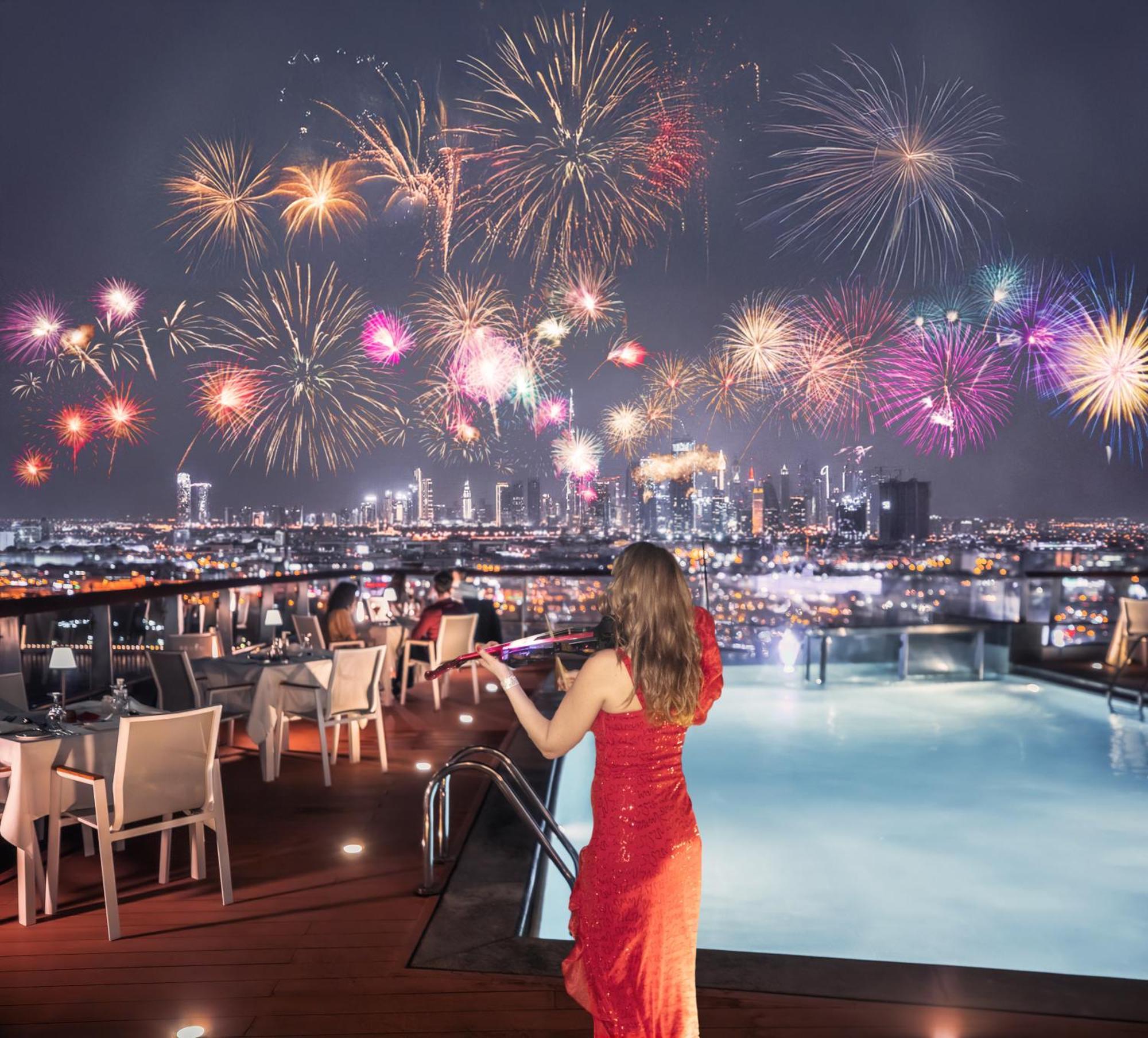 Golden Sands Boutique Hotel-Dubai Creek Екстериор снимка The photo depicts a rooftop setting with a swimming pool, where a woman in a elegant red dress stands, gazing at a stunning fireworks display lighting up the night sky. The background showcases a city skyline, sparkling with lights and buildings, whi